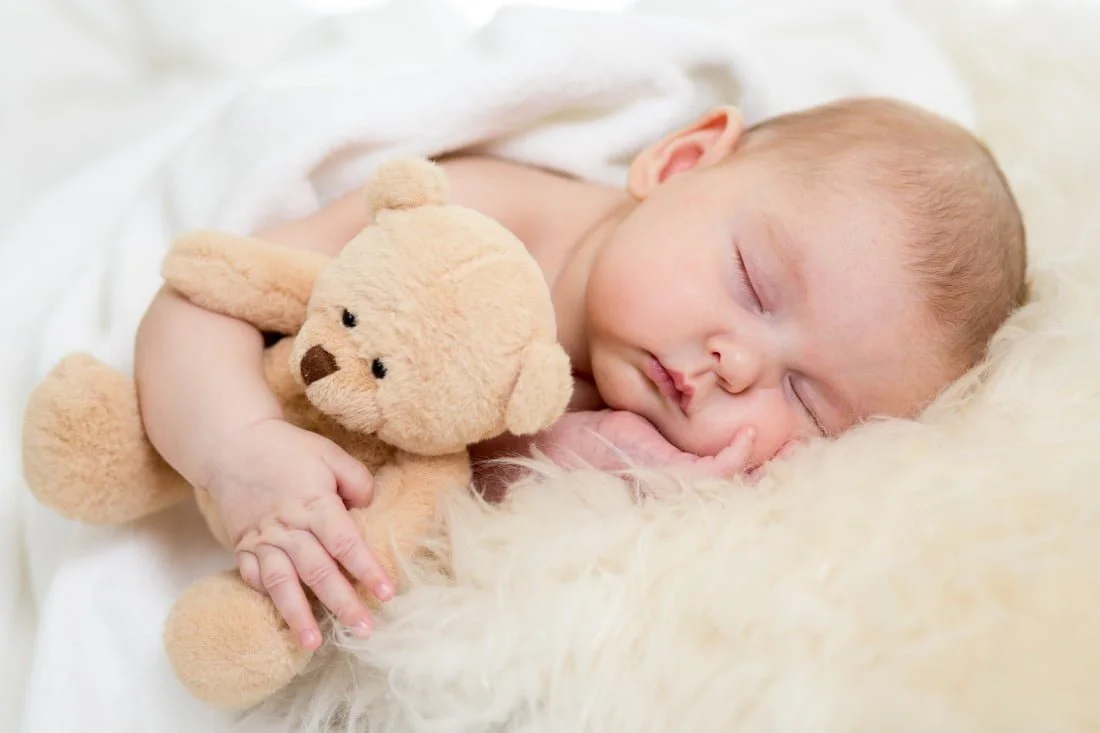 Baby der sover med sin bamse